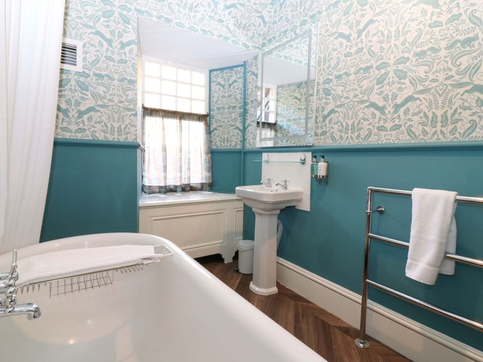 A bathroom with bathtub, sink, and towel rail at Braeriach - Mar Lodge Estate, Braemar