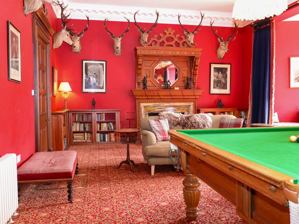 A snooker room with a green table and bookshelves at Braeriach - Mar Lodge Estate, Braemar