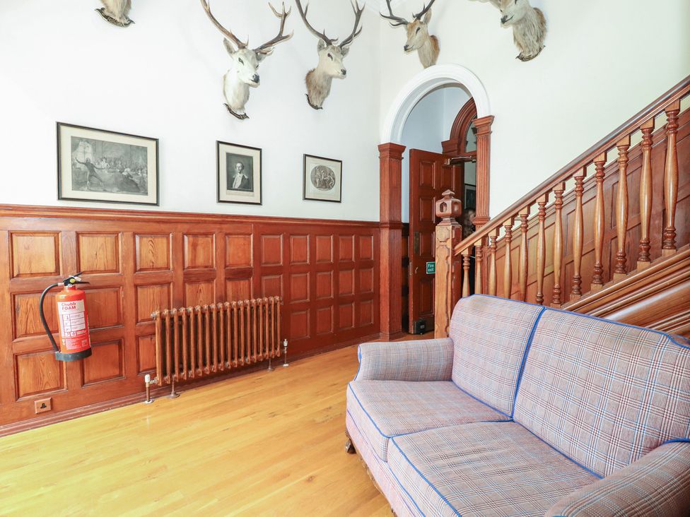 An entrance hall featuring a sofa and framed pictures at Bynack - Mar Lodge Estate in Braemar