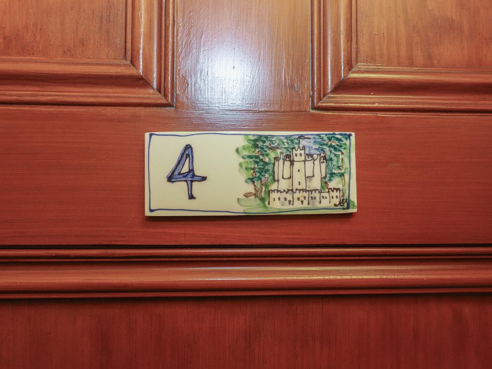 A door with a number 4 plaque featuring a castle illustration at Bynack - Mar Lodge Estate in Braemar