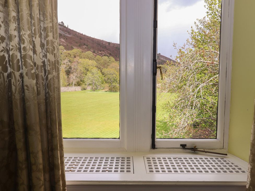 A window with a view of a field and trees at Bynack - Mar Lodge Estate in Braemar