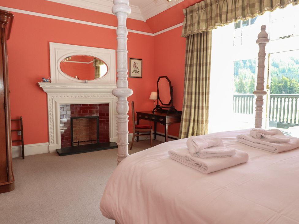 A bedroom with a fireplace and a desk at Bynack - Mar Lodge Estate in Braemar