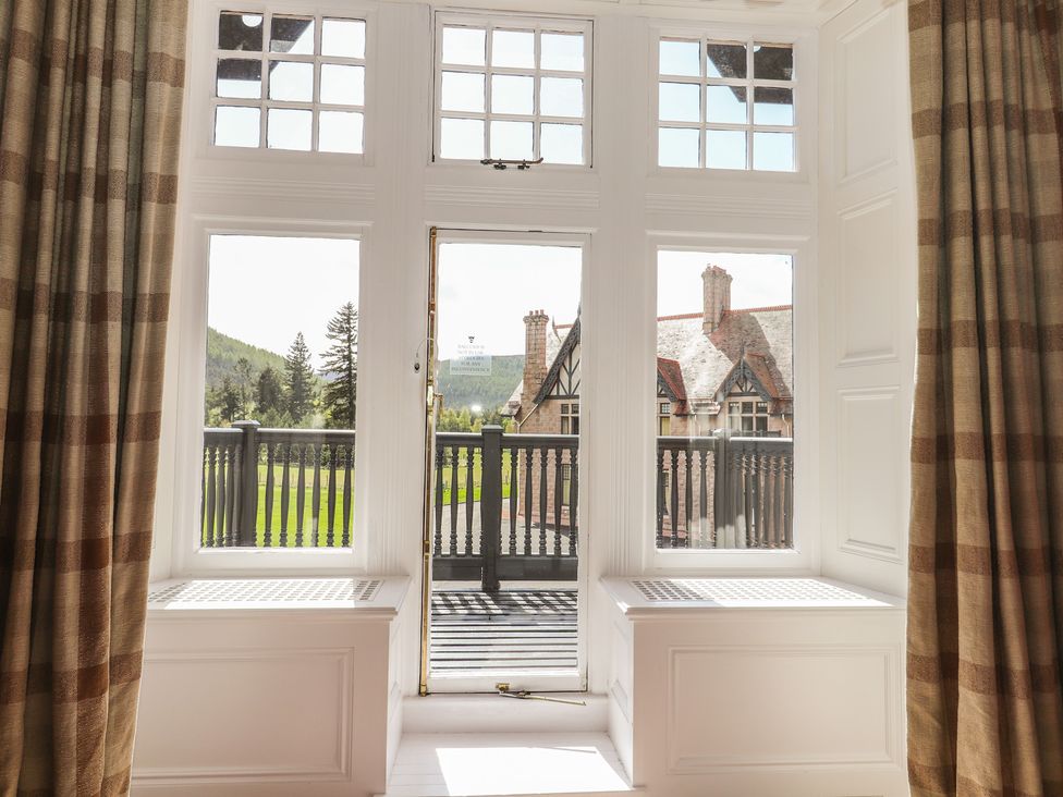 A living room with windows and a balcony at Bynack - Mar Lodge Estate in Braemar