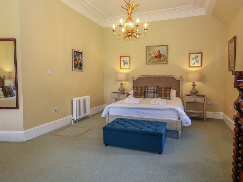 A bedroom with a bed, nightstands, and decorative paintings at Bynack - Mar Lodge Estate in Braemar