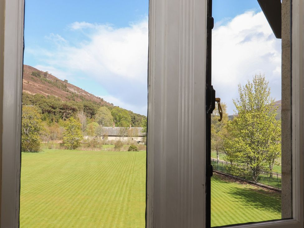 View from a window showing a mountain, grass, trees and a building at Bynack - Mar Lodge Estate, Braemar