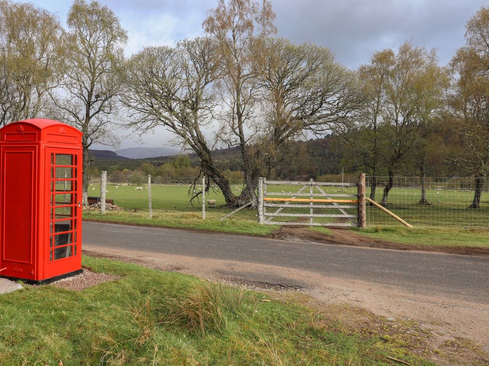 A telephone box near a fence and gate on a road at Bynack - Mar Lodge Estate, Braemar