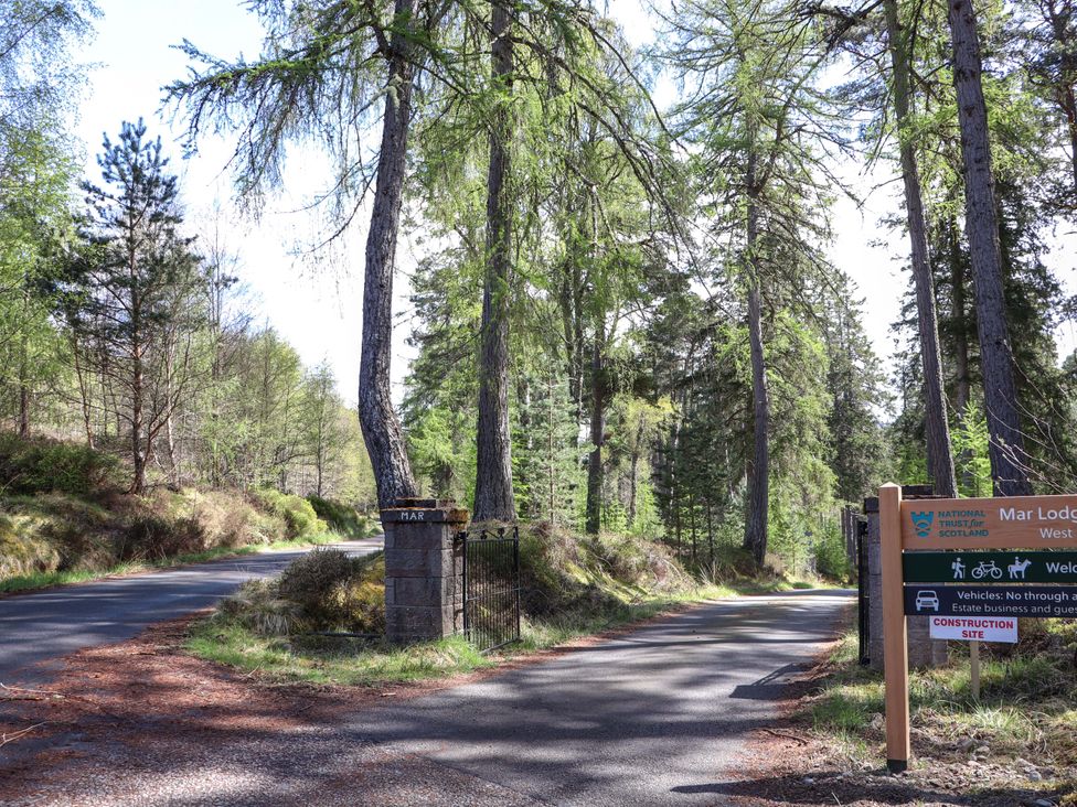 A road entrance with trees and a sign at Mar Lodge Estate in Braemar
