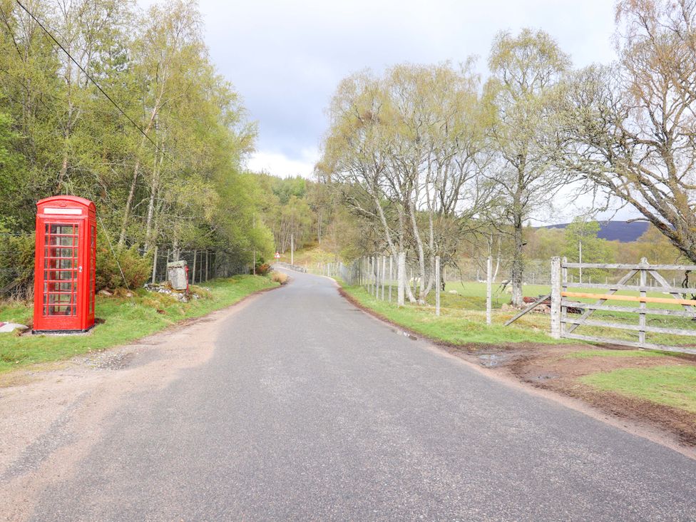 A phone booth by a road near trees and a fence at Macdui - Mar Lodge Estate in Braemar