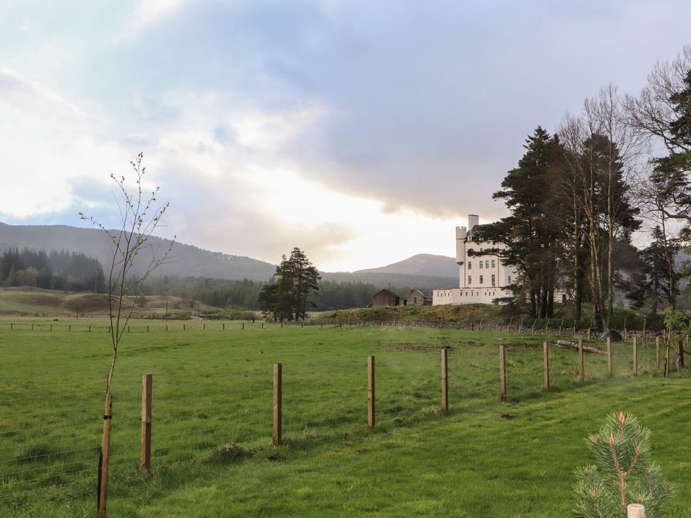 A countryside view with a building and mountains at Macdui - Mar Lodge Estate in Braemar