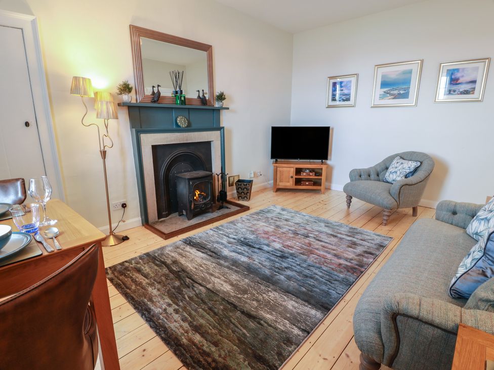 A living room with a sofa, armchair, table, and TV at North Segganwell - Culzean Castle Maybole