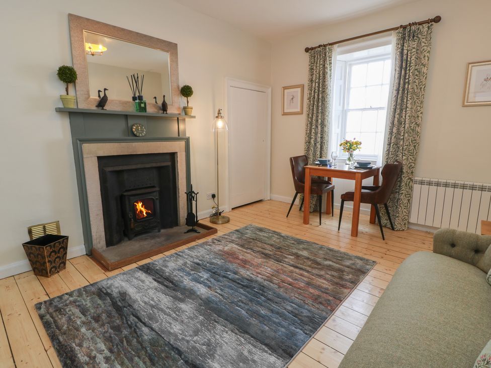A living room with a fireplace and dining table at South Segganwell - Culzean Castle Maybole