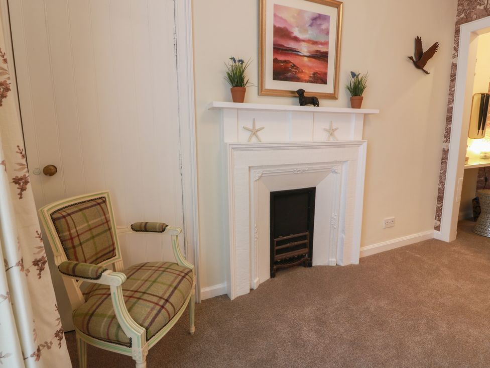 A living room with an armchair and a fireplace at South Segganwell - Culzean Castle in Maybole