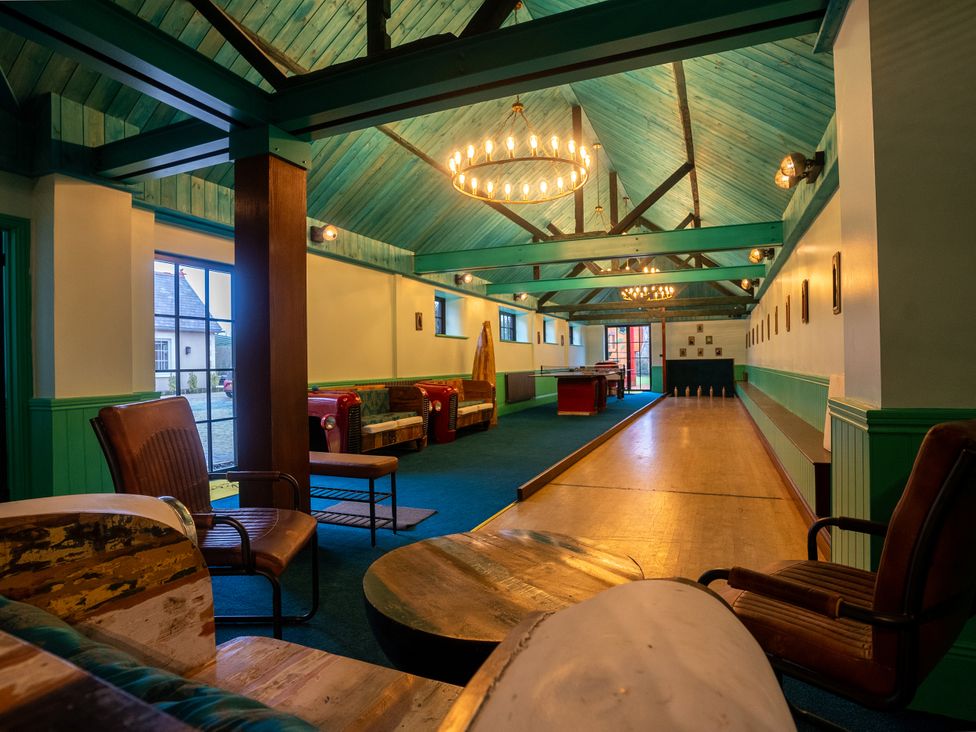 An indoor bowling area with chairs and tables at Royal Oak House in Motcombe