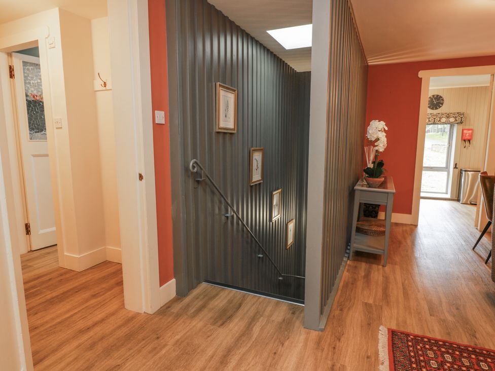 A hallway with a staircase and a side table at The Coach House - Holmwood, Glasgow