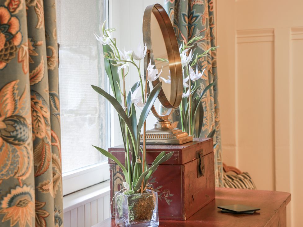 A living room with a mirror and flowers on a table at The Coach House - Holmwood Glasgow