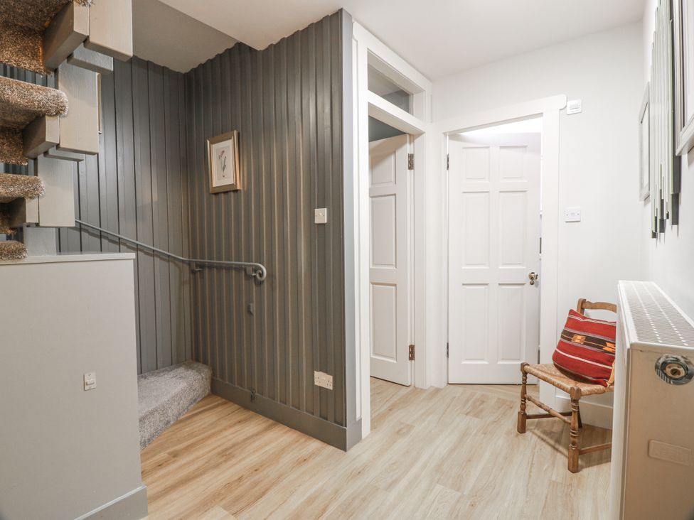A hallway with a staircase and a chair at The Coach House - Holmwood Glasgow