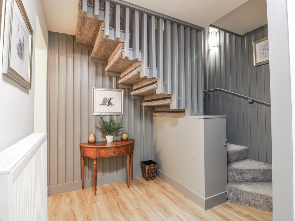 A hallway with a staircase and decorative table at The Coach House - Holmwood, Glasgow