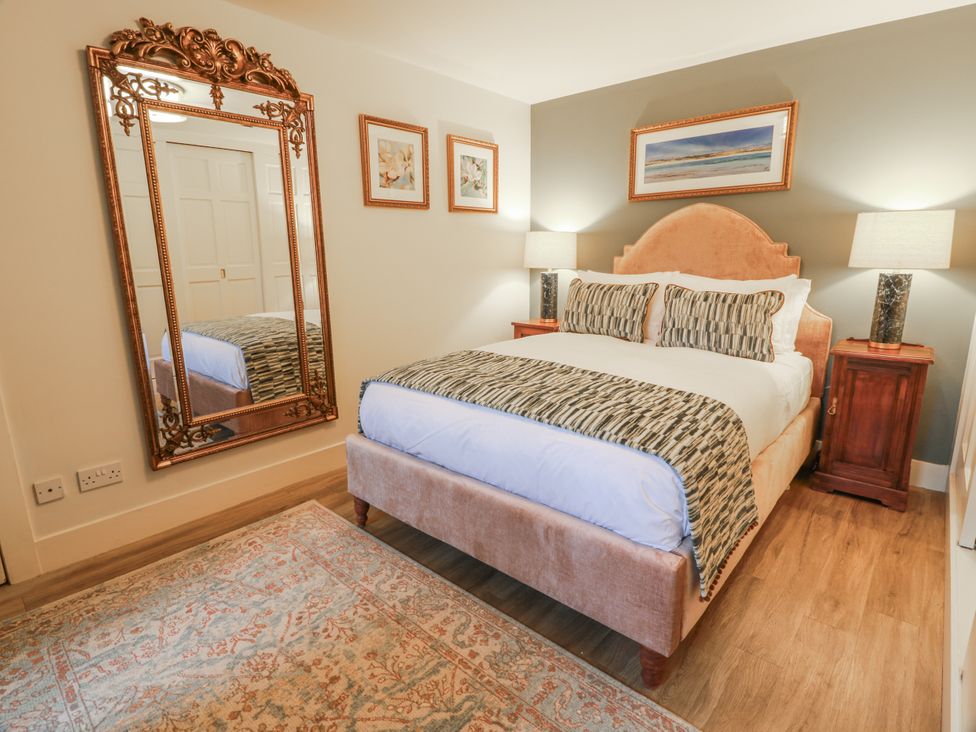 A bedroom with a bed and mirror at The Coach House - Holmwood, Glasgow