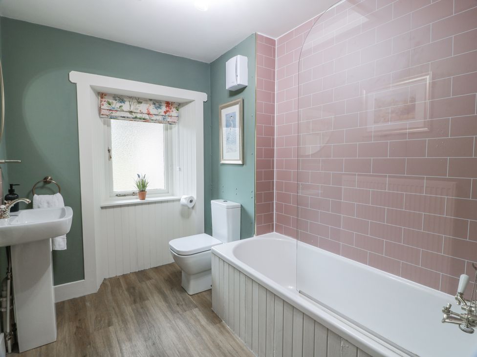 A bathroom with a bath tub, toilet, and sink at The Coach House - Holmwood Glasgow
