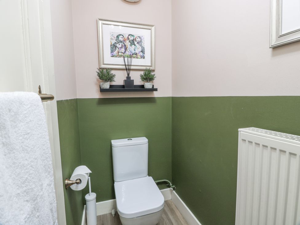 A bathroom with a toilet and a shelf displaying plants at The Coach House - Holmwood in Glasgow