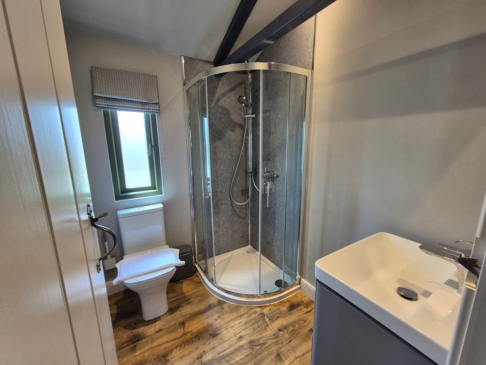 A bathroom with a shower, toilet, and wash basin at Birch Banc Retreats - Bedw Llanidloes