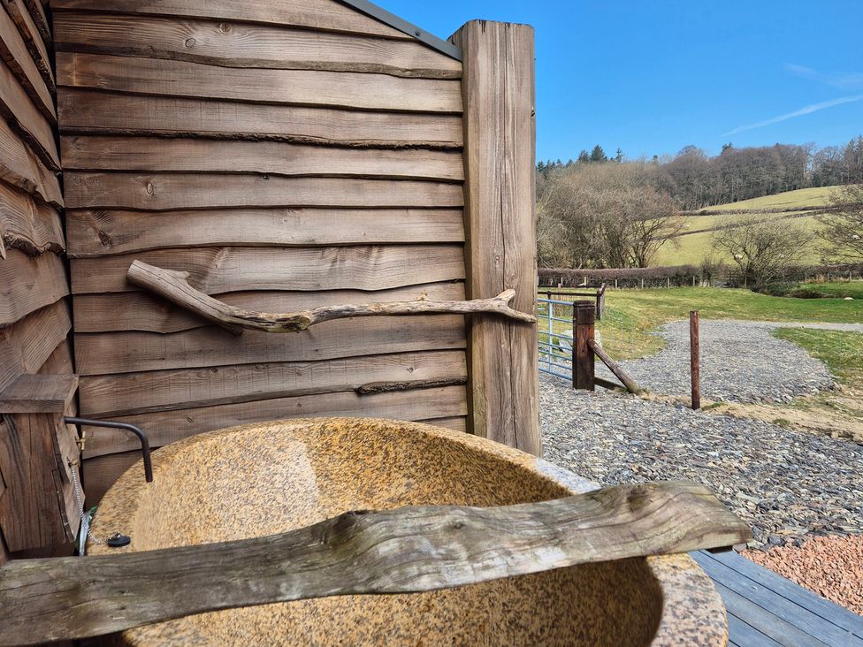 An outdoor shower area with a wooden structure and a bathtub at Birch Banc Retreats - Bedw Llanidloes