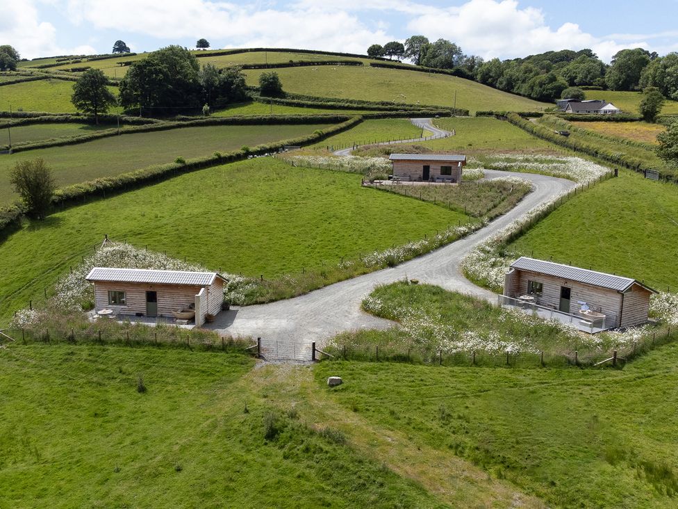 Cabins near a gravel road among fields at Birch Banc Retreats - Bedw Llanidloes