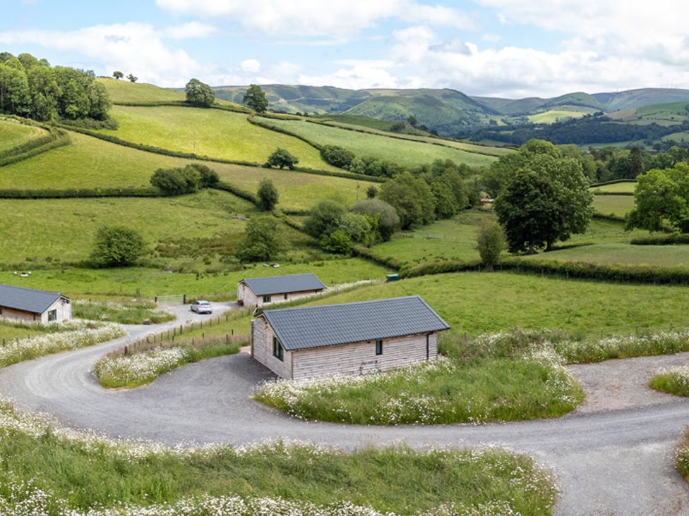 An outdoor view of cabins and fields at Birch Banc Retreats - Bedw Llanidloes