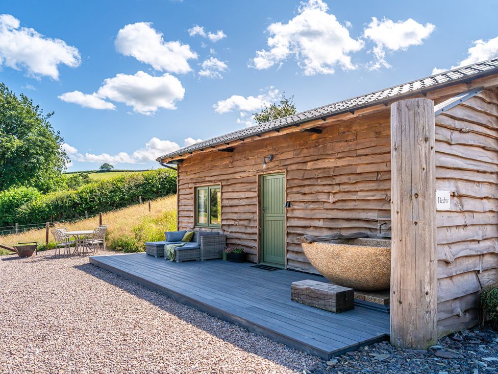 An outdoor area with a wooden hut and seating at Birch Banc Retreats - Bedw Llanidloes