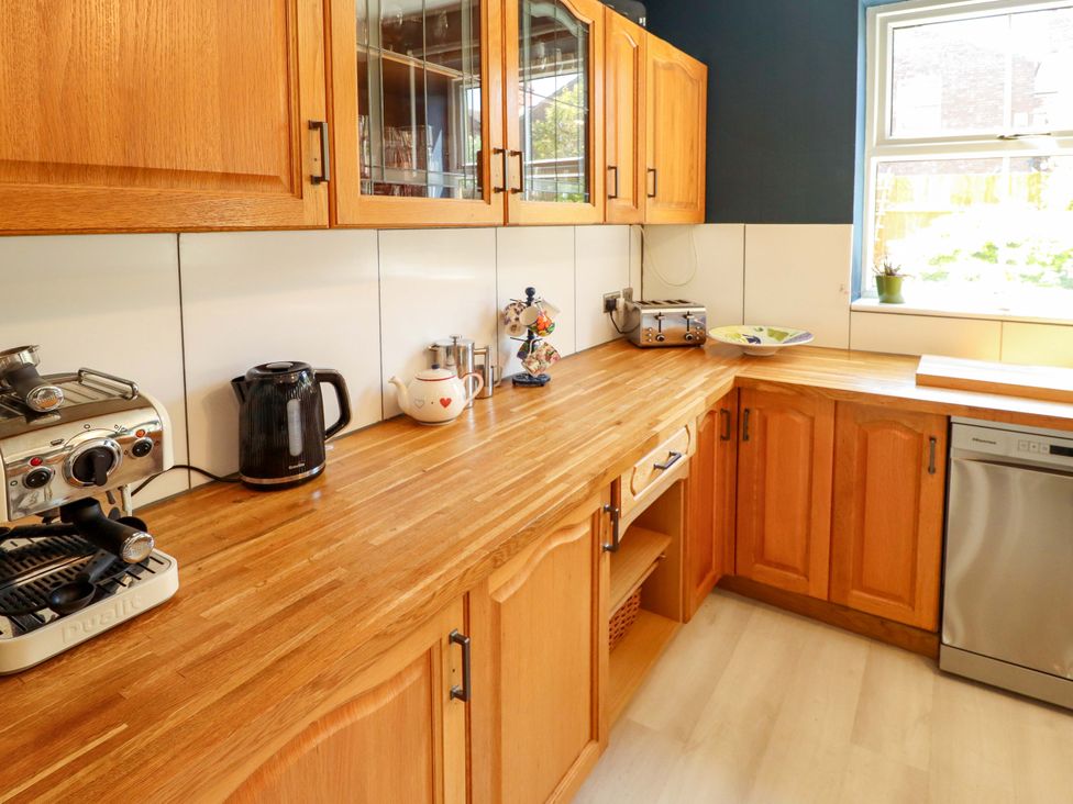 A kitchen with wooden cabinets and various appliances at Maples in Hunstanton