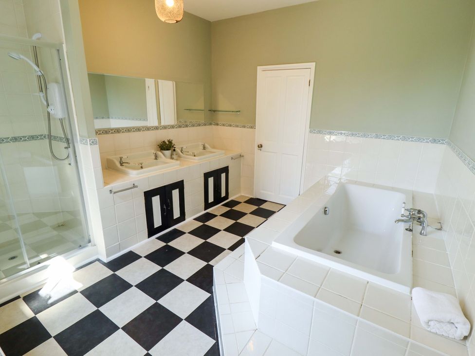 A bathroom with two sinks, a shower, and a bathtub at Maples in Hunstanton