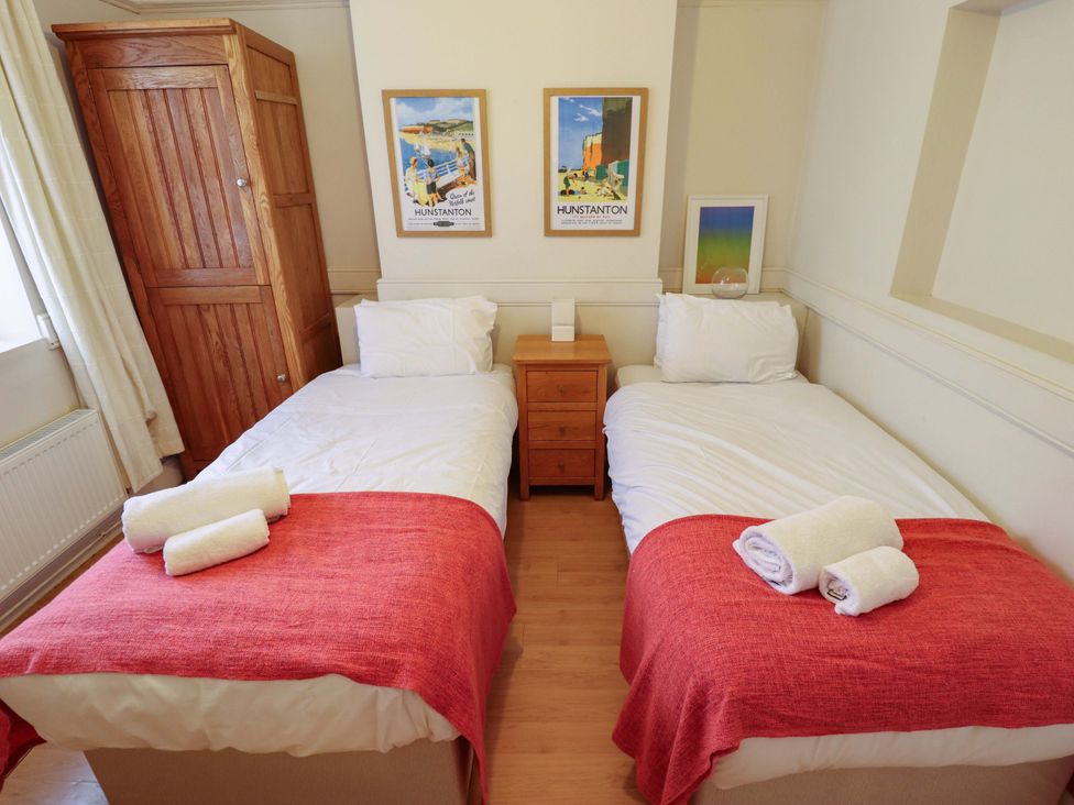 A bedroom with two beds, a wardrobe, and a nightstand at Maples in Hunstanton