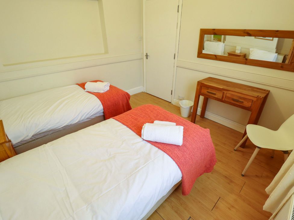 A bedroom with two beds and a wooden table at Maples in Hunstanton