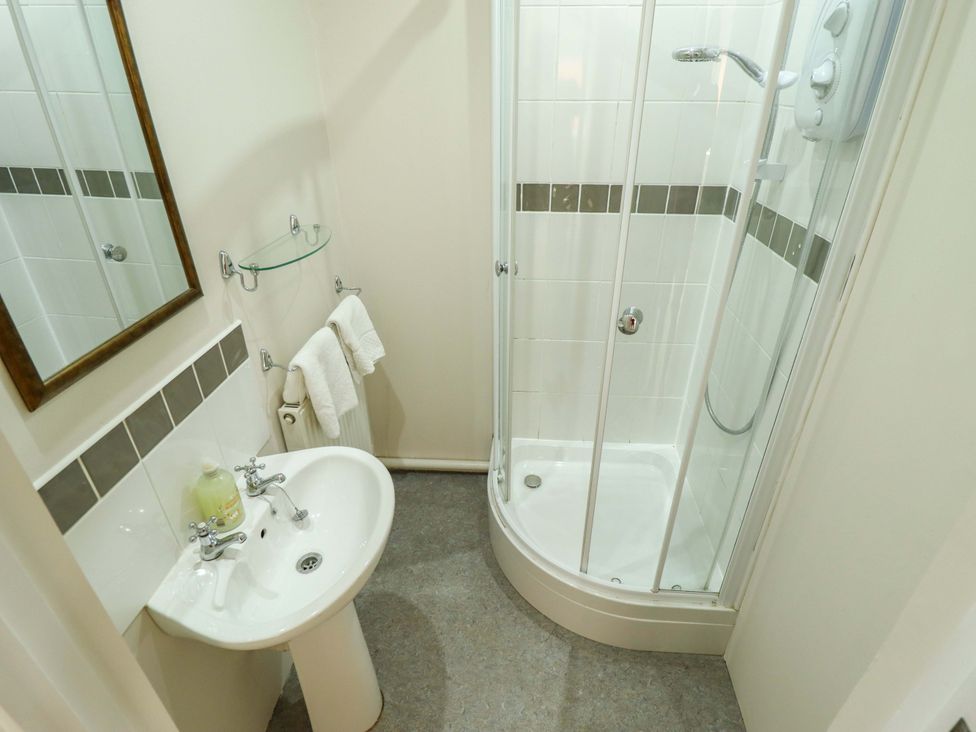 A bathroom featuring a shower, sink, and mirror at Maples in Hunstanton