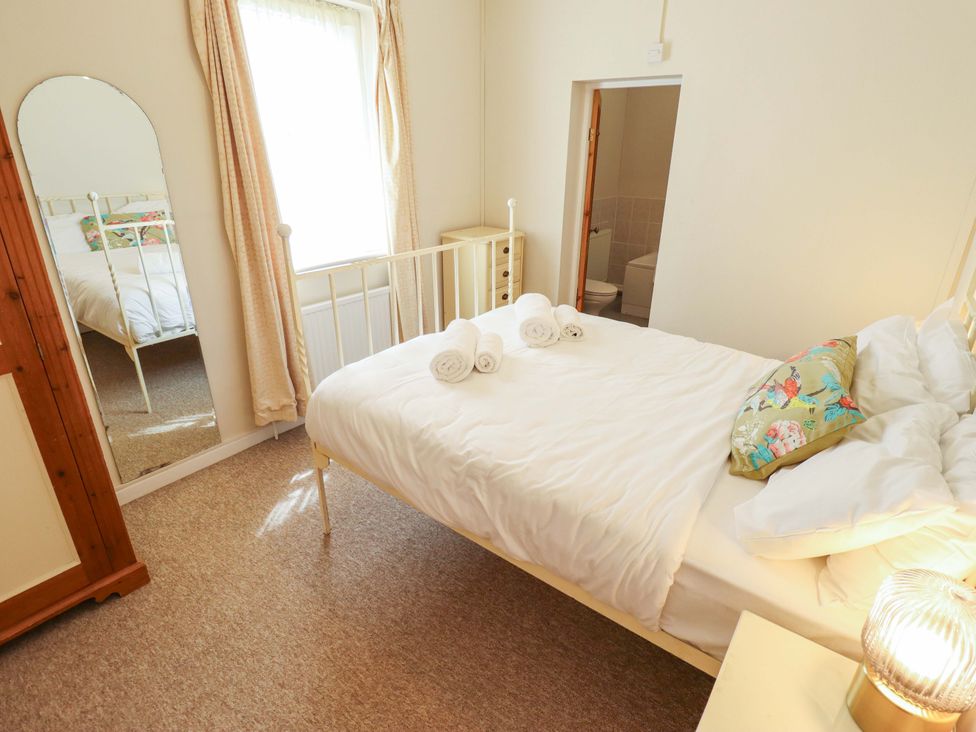 A bedroom with a bed and mirror at Maples in Hunstanton
