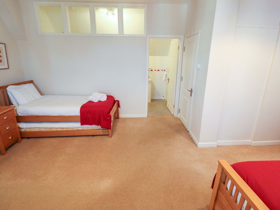 A bedroom with two beds and a bathroom door at Maples in Hunstanton