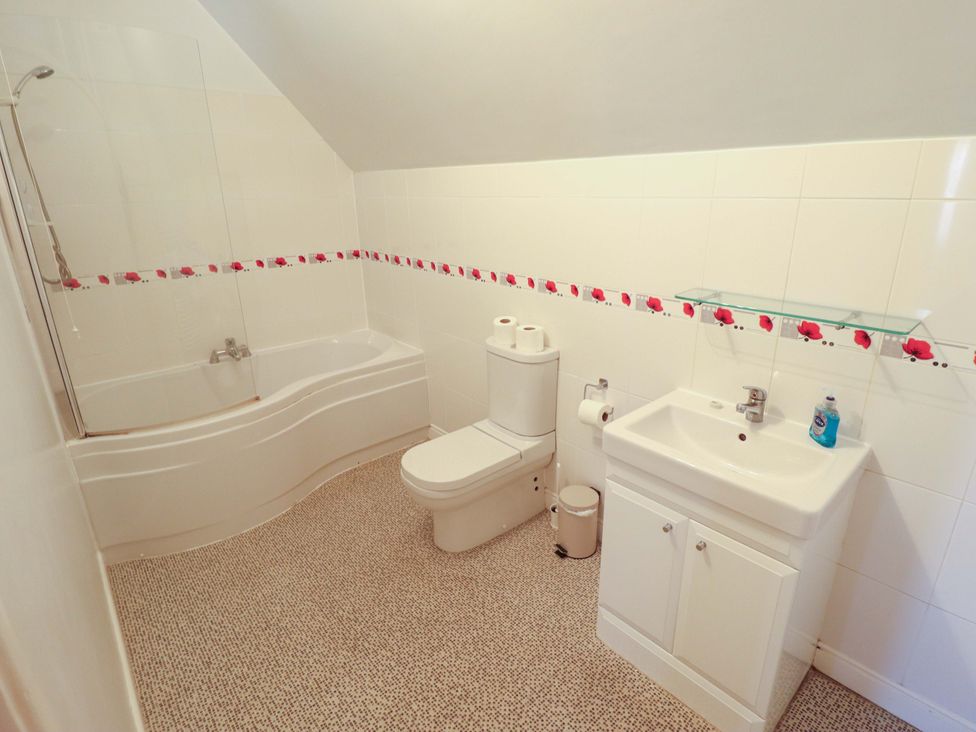 A bathroom with a bathtub, toilet, and sink at Maples, Hunstanton