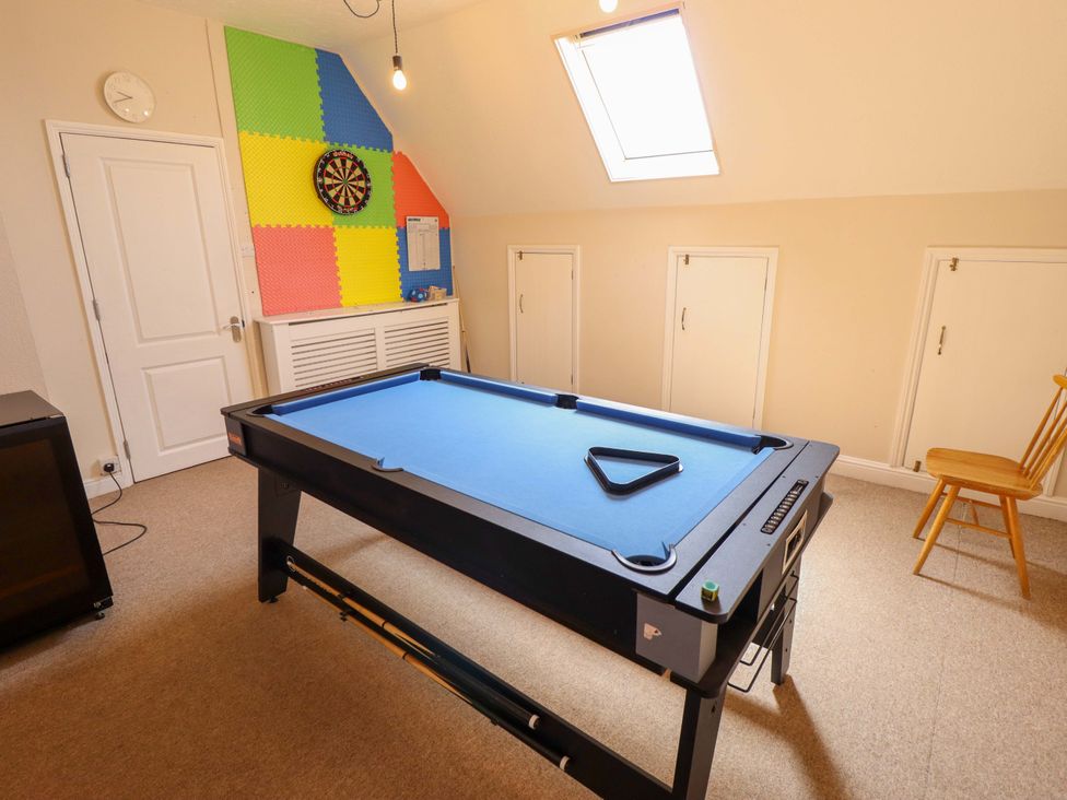 A game room with a pool table and dartboard at Maples in Hunstanton