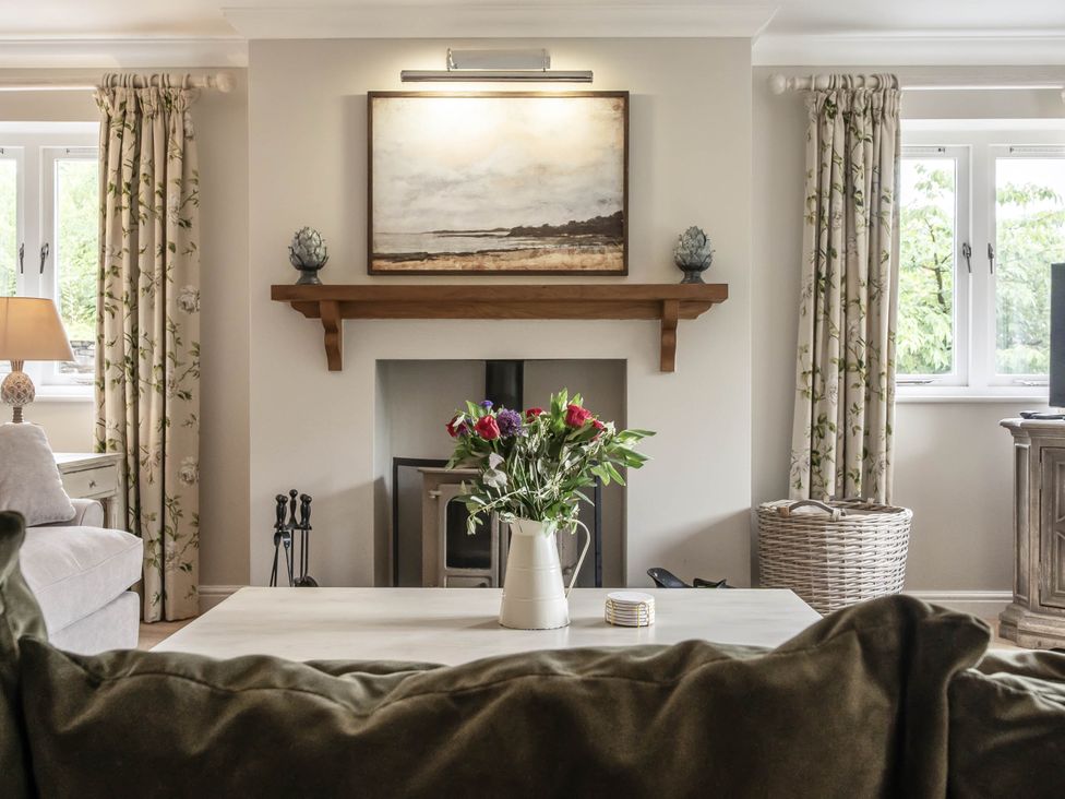 A living room with a coffee table and flowers at Cunsey Lodge at the Graythwaite Estate near Hawkshead