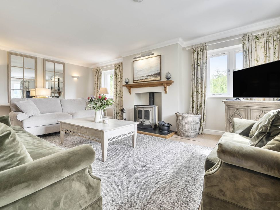 A living room with a fireplace and a television at Cunsey Lodge at the Graythwaite Estate near Hawkshead