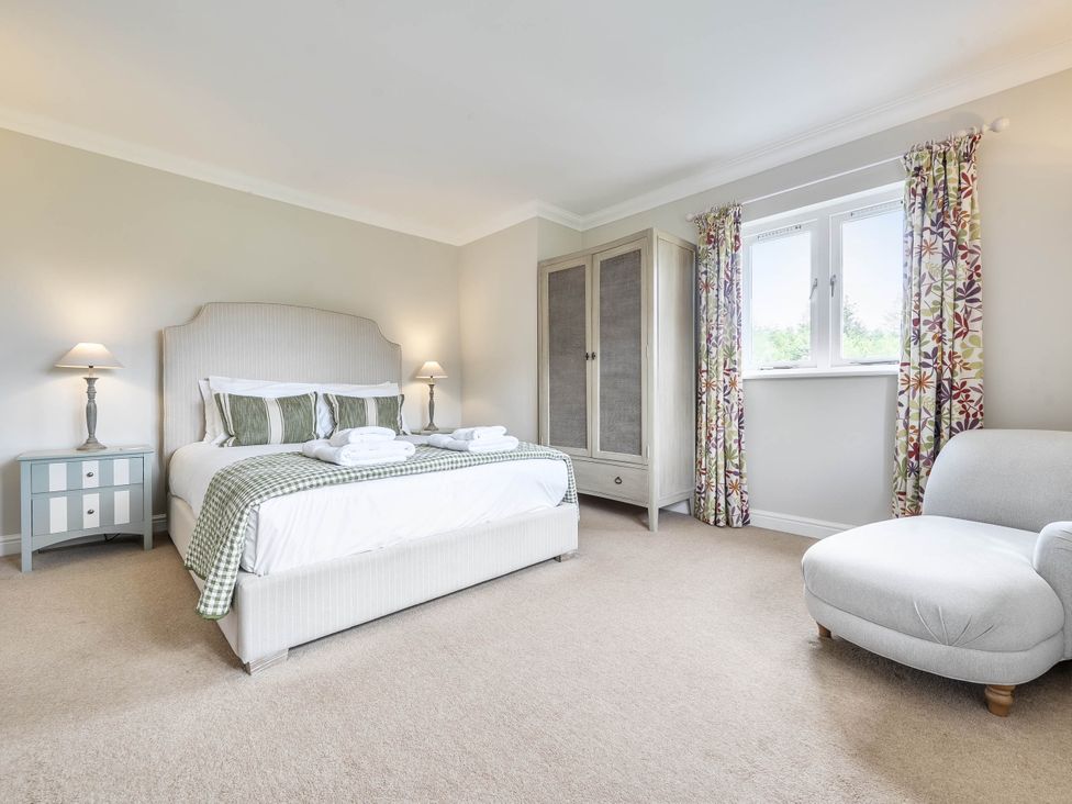 A bedroom with a bed, bedside table, and wardrobe at Cunsey Lodge at the Graythwaite Estate near Hawkshead