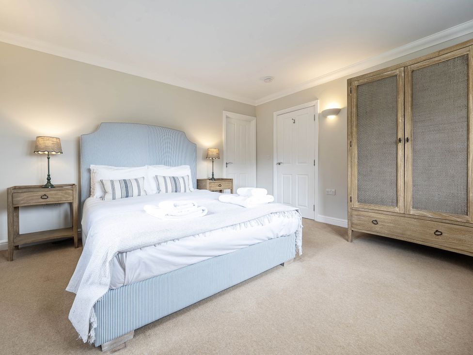 A bedroom with a bed and wardrobe at Cunsey Lodge at the Graythwaite Estate near Hawkshead