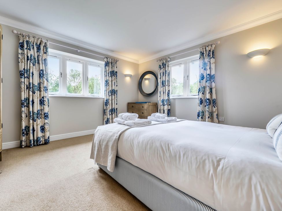 A bedroom with a bed and windows at Cunsey Lodge at the Graythwaite Estate near Hawkshead