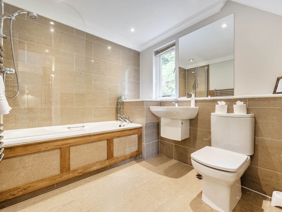 A bathroom with a bathtub, sink, toilet and towel rail at Cunsey Lodge at the Graythwaite Estate