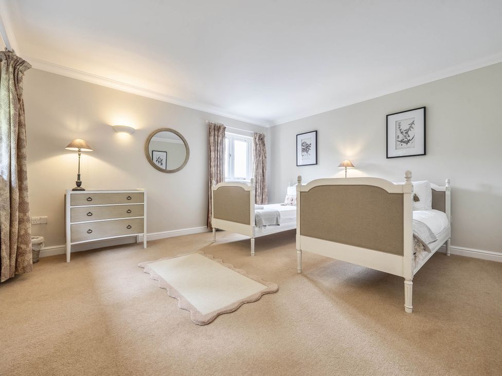 A bedroom with two beds and a dresser at Cunsey Lodge at the Graythwaite Estate near Hawkshead