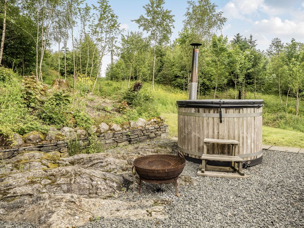 An outdoor area with a hot tub and fire pit at Cunsey Lodge at the Graythwaite Estate near Hawkshead