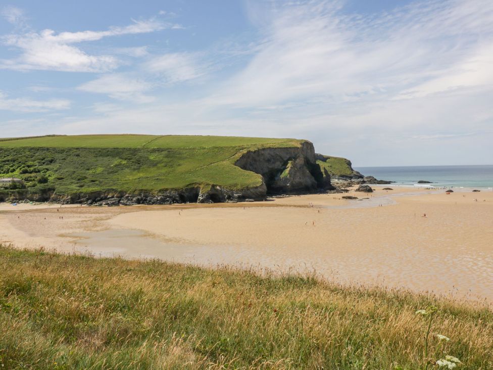 A sandy beach with grassy cliffs and the ocean at 49 Atlantic Reach in Newquay