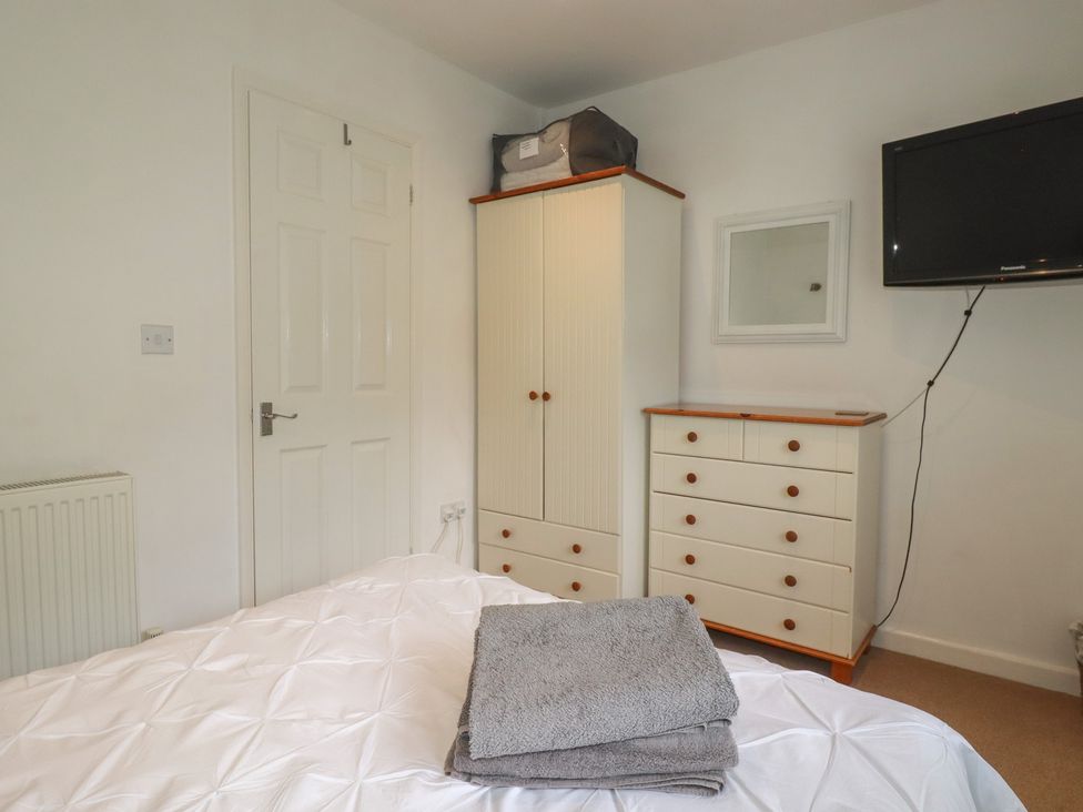 A bedroom with a bed, wardrobe, dresser, and television at 49 Atlantic Reach, Newquay