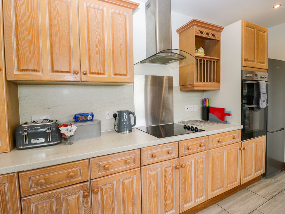 A kitchen with wooden cabinets, countertop, kettle, toaster, and fridge at Sherriff, Troutbeck, near Keswick