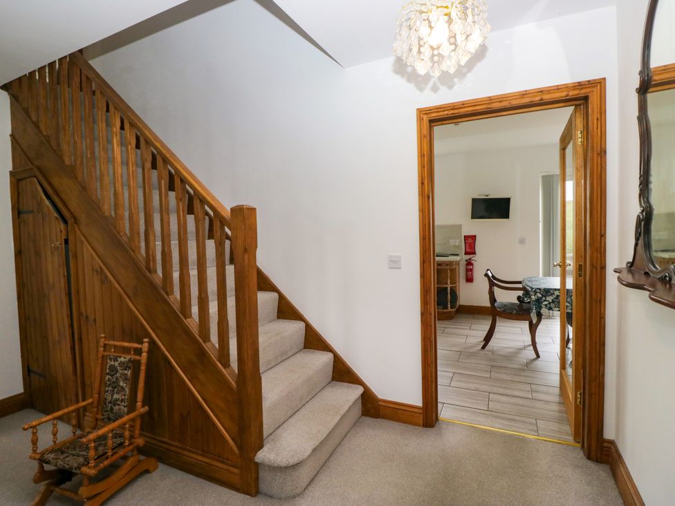 A hallway with a staircase and a rocking chair at Sherriff, Troutbeck, near Keswick